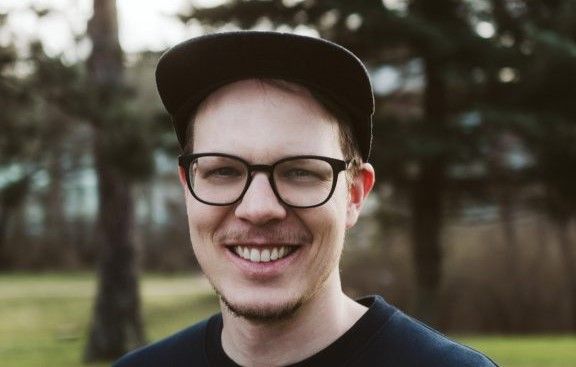 Porträt von Christopher Zobel, lächelnd, im Freien vor Bäumen